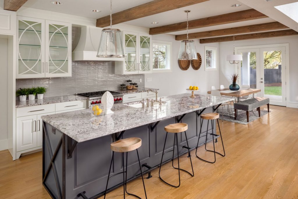 Beautiful Kitchen With white ice granite countertops In New Luxury Home With Island Pendant Lights And Glass Fronted