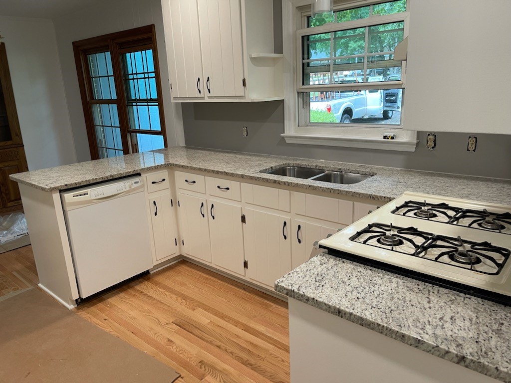 The kitchen is made in a light style with white cabinets and granite kitchen countertops