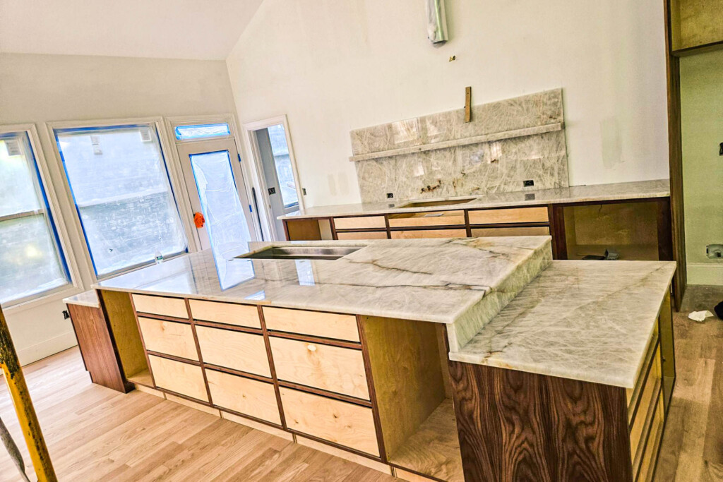 Modern kitchen island and countertops under construction with marble tops.