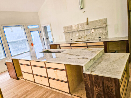 Modern kitchen island and countertops under construction with marble tops.