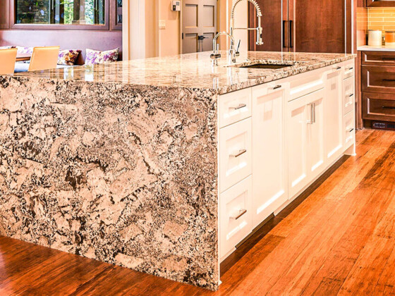 Modern kitchen island with granite countertop and white cabinets.