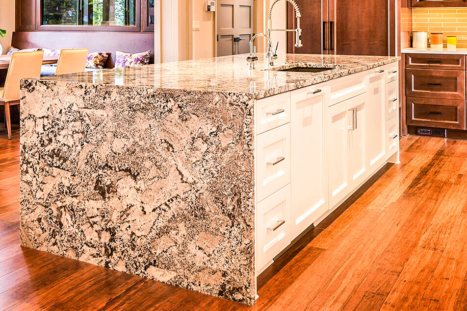 Modern kitchen island with granite countertop and white cabinets.