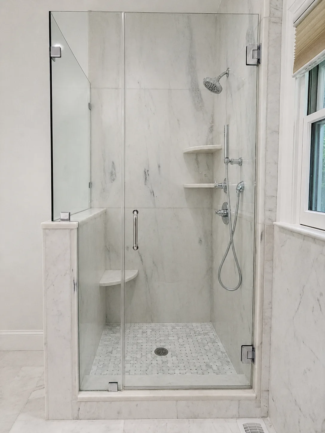 Carrara marble slab shower with a mosaic shower floor
