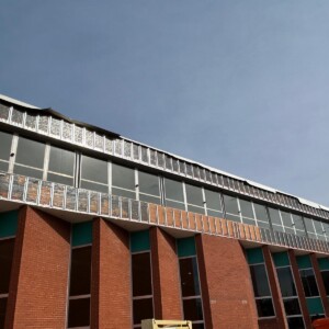 A modern brick building with large windows and metallic accents under a clear sky.
