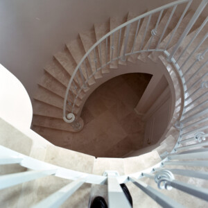 Top view of a beige spiral staircase with white railings.