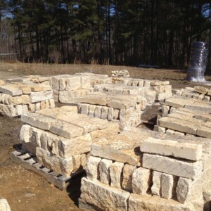 Stacks of rough-cut limestone blocks arranged outdoors on pallets.