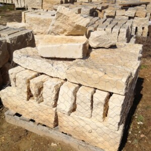 Stacked limestone blocks secured with wire mesh on a pallet outdoors.