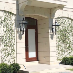 Elegant entrance with climbing plants and classic lanterns on a cream facade.