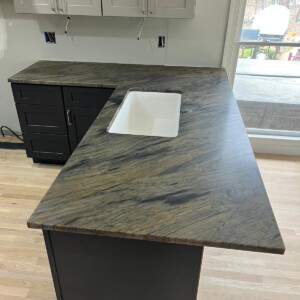 Modern kitchen island with dark marble countertop and white sink.