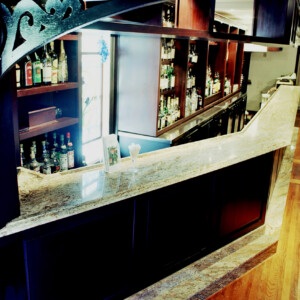 Elegant marble countertop bar with wooden shelves and liquor bottles.