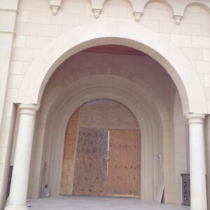 Arched entrance with columns, boarded up with wooden panels.