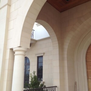 Elegant stone arches and columns frame a building entrance with tall windows.