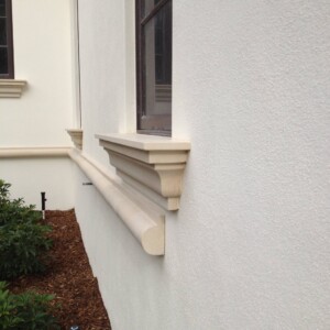 Close-up of decorative exterior wall molding and window ledge on a white building.