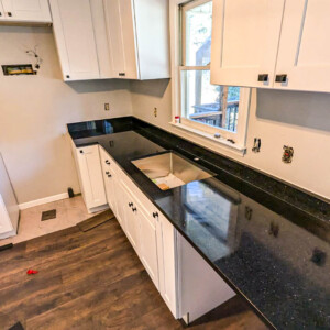 Newly installed black granite countertops in a white kitchen under renovation.