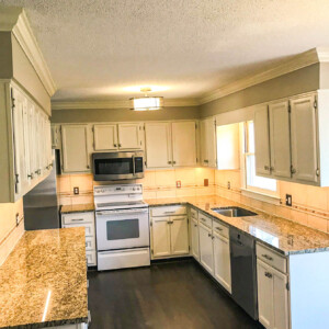 Modern kitchen with granite countertops and white cabinets.