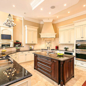 Elegant kitchen with a dark island and light cabinetry under warm lighting.