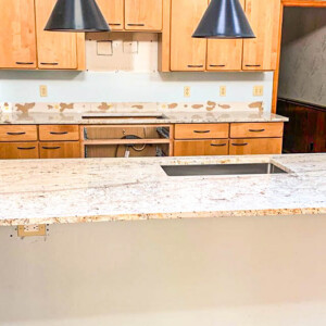 Modern kitchen island with granite countertop and wooden cabinetry in progress.
