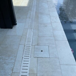 Clean tiled poolside area with a drainage grate and water visible.