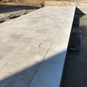 A newly paved stone patio area with a water feature on the side.