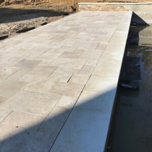 A newly paved stone patio area with a water feature on the side.