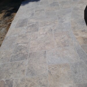 Close-up of beige stone tile flooring with varied rectangular patterns.