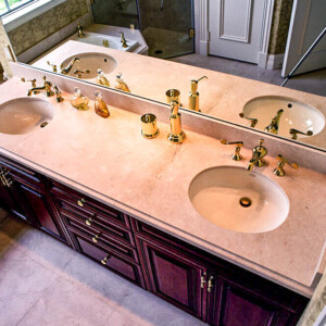 Double sink bathroom vanity with gold fixtures and large mirror.