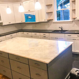 Modern kitchen with white cabinets and a large marble island.