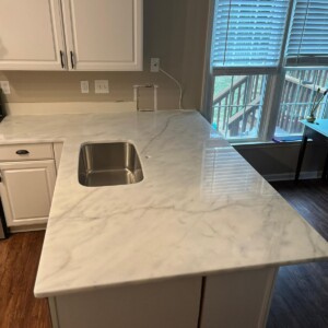 Modern kitchen with a white marble countertop and stainless steel sink.