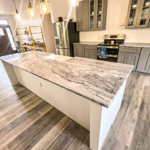 Modern kitchen with a large marble island and gray cabinetry.