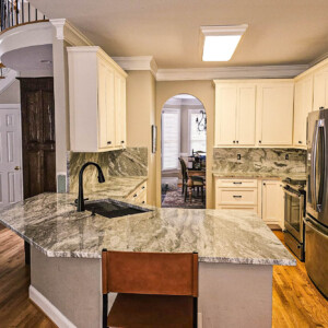 Modern kitchen with marble countertops, white cabinets, and stainless steel appliances.