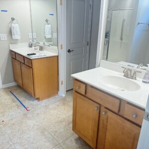 Bathroom with wooden cabinets and dual sinks separated by a door.