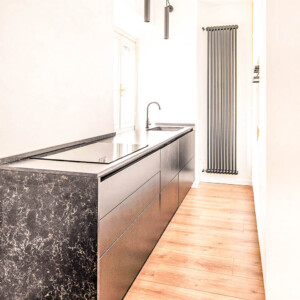 Sleek modern kitchen with black marble island and wooden floor.