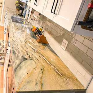 Long kitchen countertop with a natural stone surface and white cabinets.