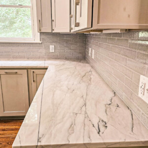 Modern kitchen countertop with marble surface and gray subway tile backsplash.