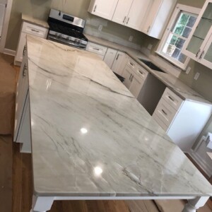 Sleek marble kitchen countertops with white cabinetry and stainless steel appliances.