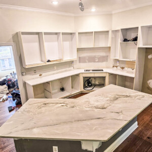 Kitchen under renovation with new marble countertops and unfinished cabinetry.