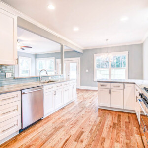 Bright modern kitchen with white cabinets and hardwood floors.