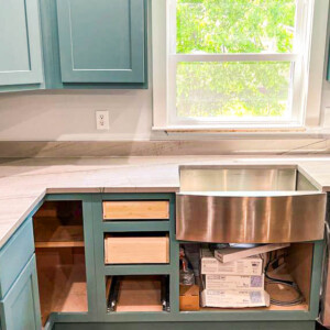 Kitchen countertop with a farmhouse sink and unfinished cabinet drawers.