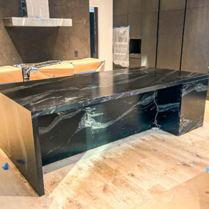 Modern kitchen island with sleek black marble countertop in a minimally designed kitchen.