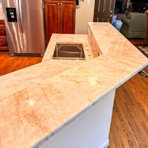 Polished marble kitchen countertop with built-in sink and wooden cabinets.