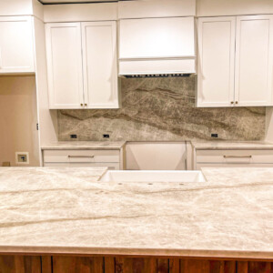 Modern kitchen with white cabinets and marble countertops.