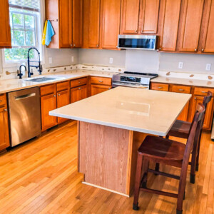 Modern kitchen with wooden cabinets, island, and stainless steel appliances.