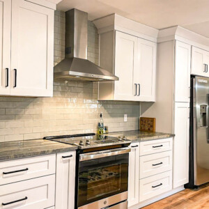 Modern kitchen with white cabinets, stainless steel appliances, and wooden flooring.