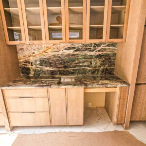 Kitchen countertop and cabinets with marble backsplash and sink.