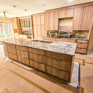 Modern kitchen with a large marble island and wooden cabinets.