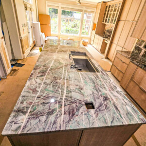 A spacious kitchen island with a polished marble countertop and built-in sink.