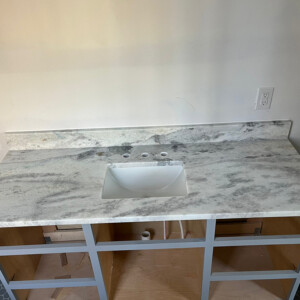 New marble countertop with sink installed on a wooden vanity frame.