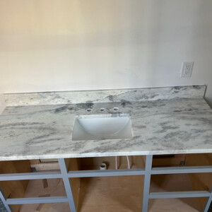New marble countertop with sink installed on a wooden vanity frame.