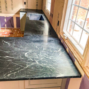 Black marble countertop with white veins in a kitchen under construction.