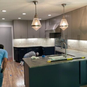 Workers installing or renovating a modern kitchen with two-tone cabinets.
